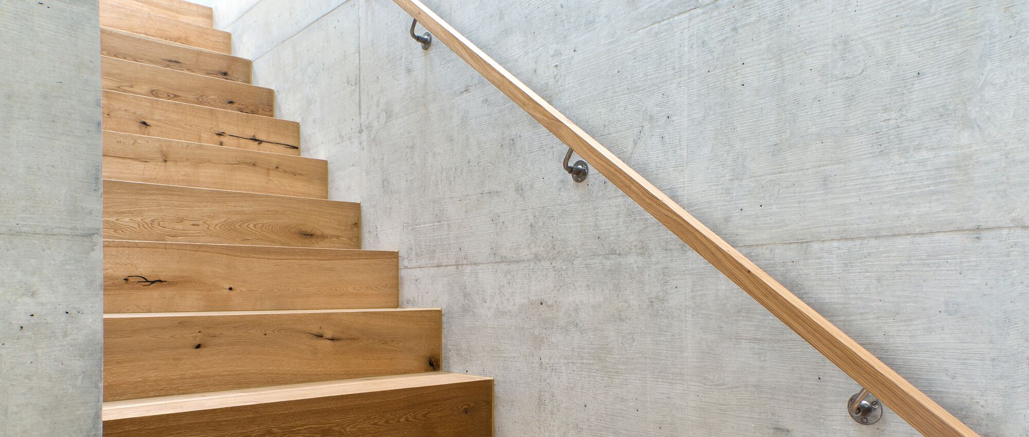 Eine Holztreppe und ein Treppengeländer aus Holz in einem modernen Neubau