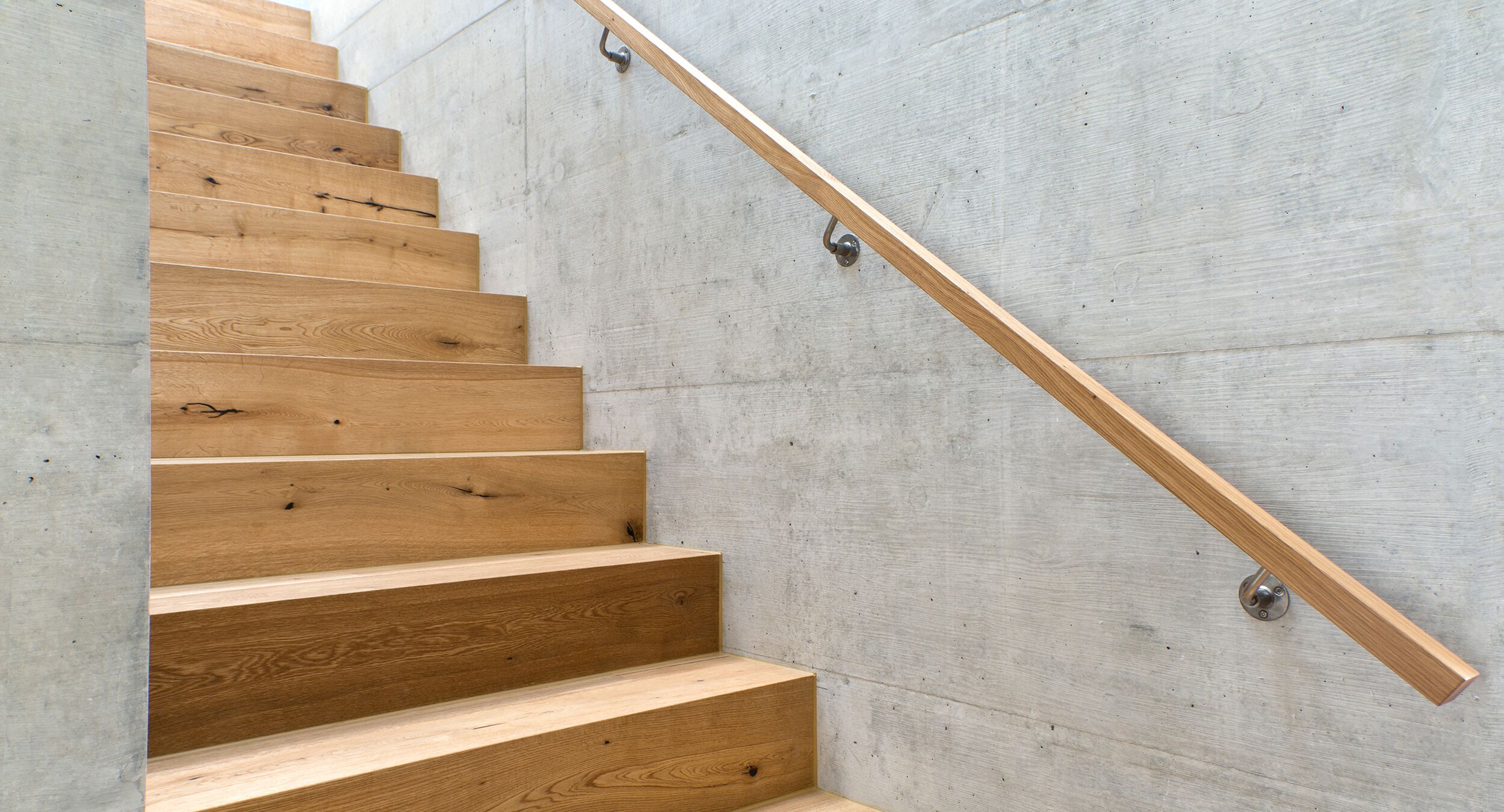 Eine Holztreppe und ein Treppengeländer aus Holz in einem modernen Neubau